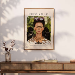 Frida Kahlo Self Portrait with Thorn Necklace and Hummingbird Print displayed on a wall above a wooden console table.
