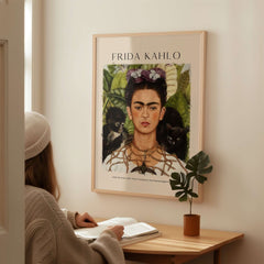 Frida Kahlo Self Portrait with Thorn Necklace and Hummingbird Print displayed on a wall, woman admiring the art poster.