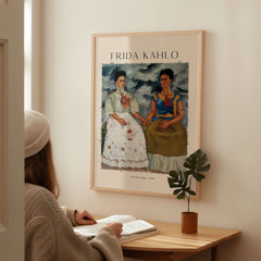 Frida Kahlo The Two Fridas Famous Art Print Poster Wall Art displayed in a cozy interior with a woman seated and reading.