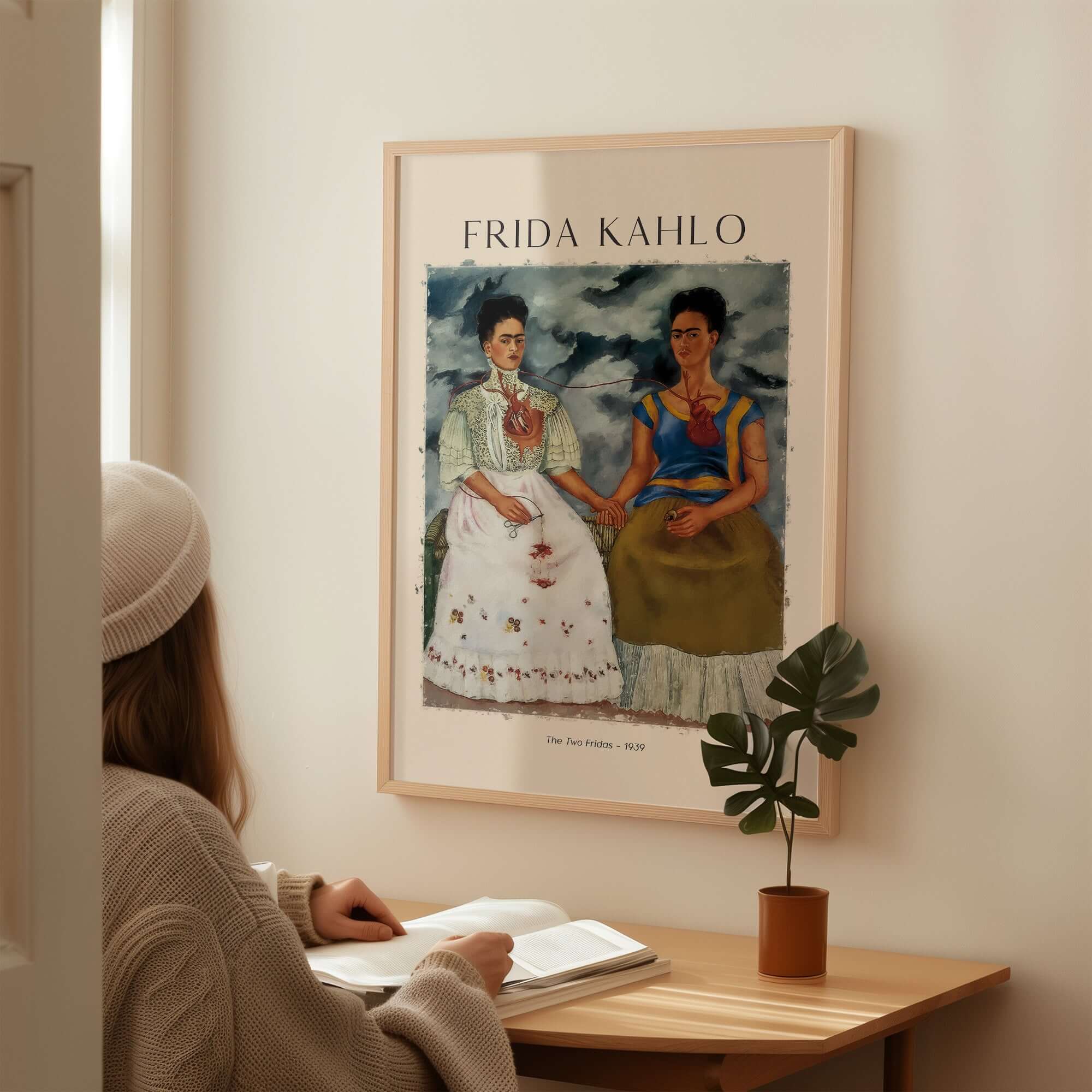 Frida Kahlo The Two Fridas Famous Art Print Poster Wall Art displayed in a cozy interior with a woman seated and reading.