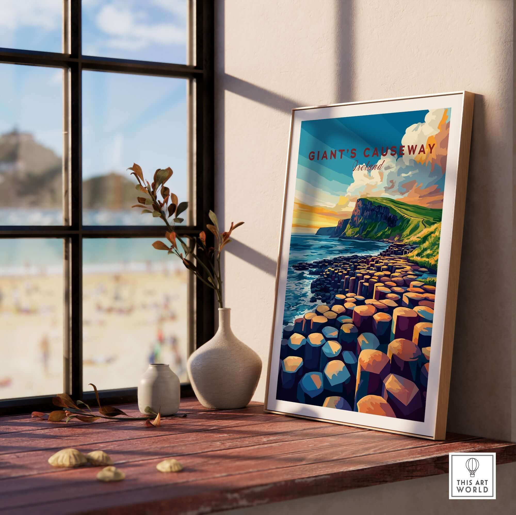 Giant's Causeway Travel Print displayed on a window sill with a scenic beach view.