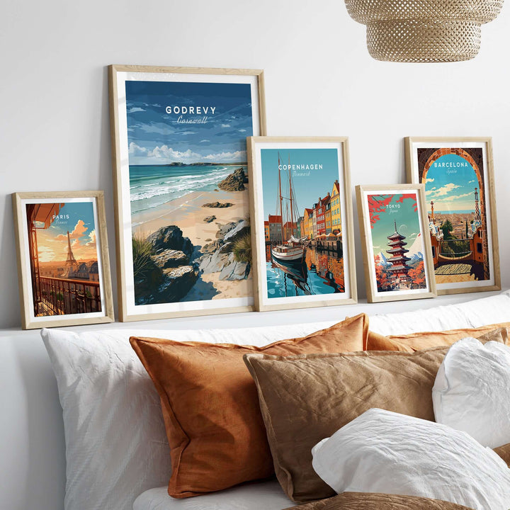 Framed Godrevy Beach and city posters on a wall above a cozy couch with decorative pillows.
