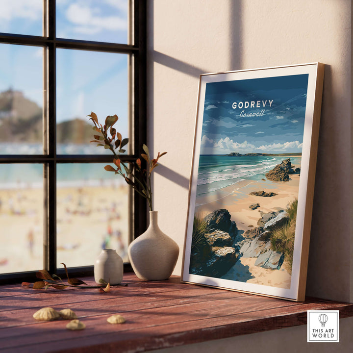 Godrevy Beach poster featuring a serene coastal scene displayed on a wooden shelf near a window.