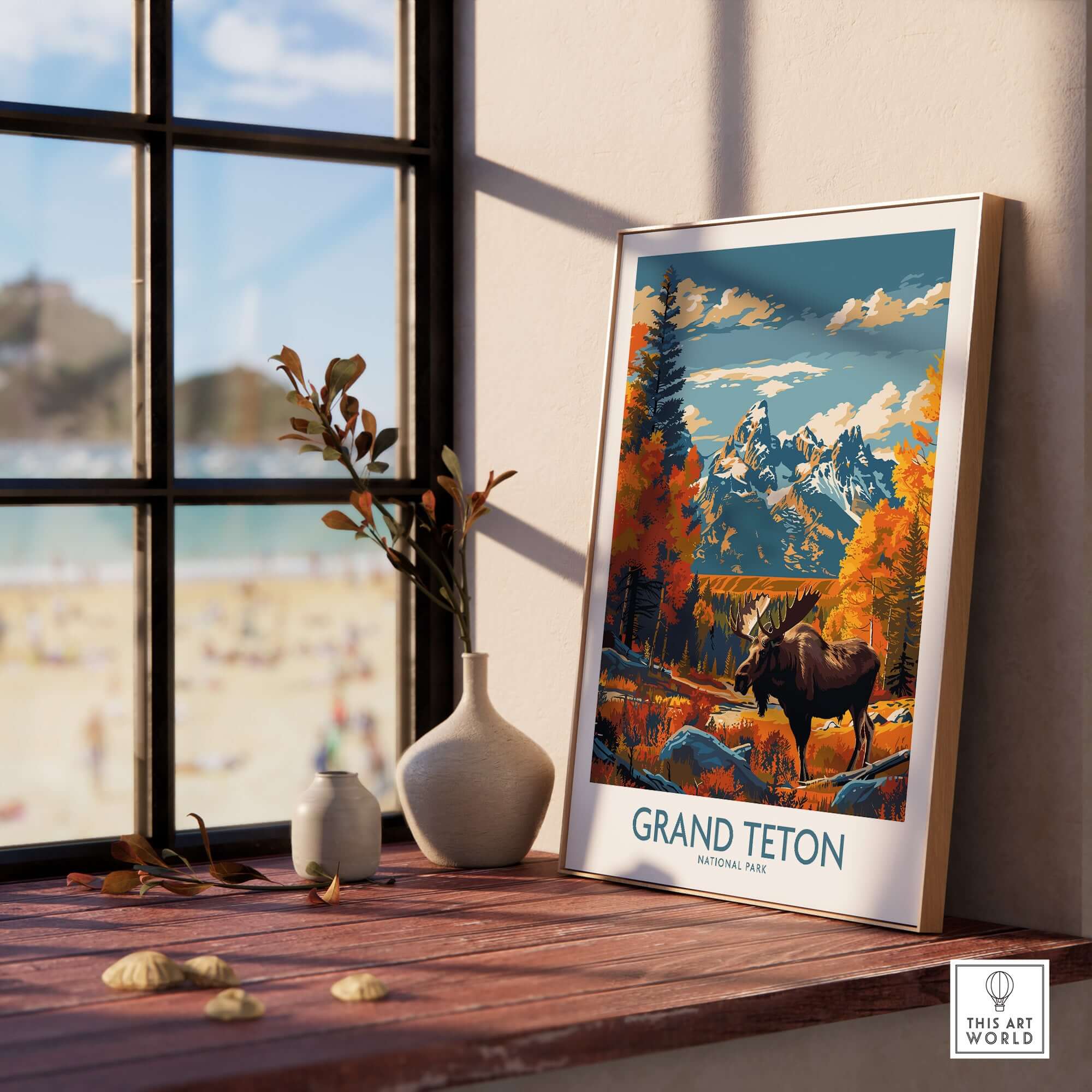 Grand Teton Wall Art - National Park Poster displayed on a wooden table near a window with a beach view.