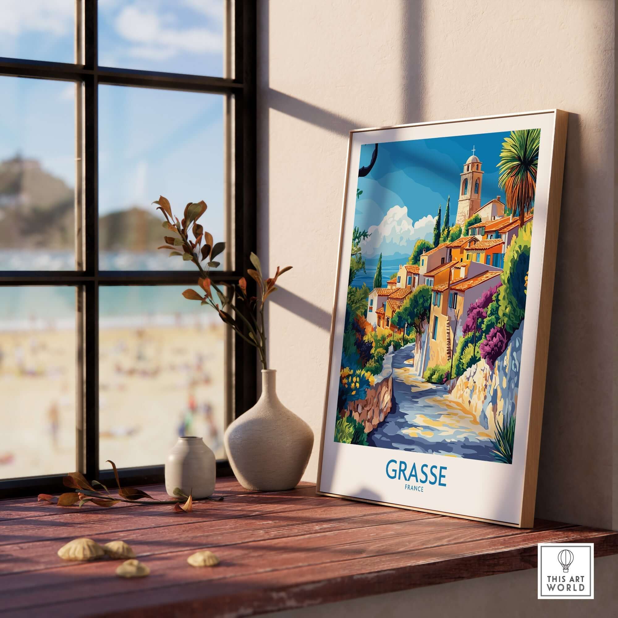 Grasse Travel Poster displayed on a wooden surface by a window, showcasing vibrant colors and scenic views of Grasse, France.