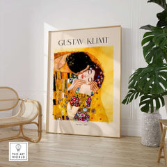 Gustav Klimt Art Print - The Kiss 1907 displayed in a stylish interior with artistic decor and plants.