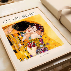 Gustav Klimt Art Print - The Kiss 1907 showcased on a table with elegant packaging.