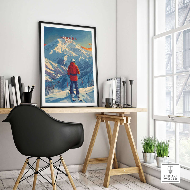 Modern workspace featuring framed Hakuba ski poster on wall, with wooden desk and black chair by a bright window.