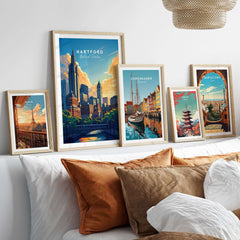 Hartford Travel Print displayed among other travel posters in a stylish bedroom setting with decorative pillows.
