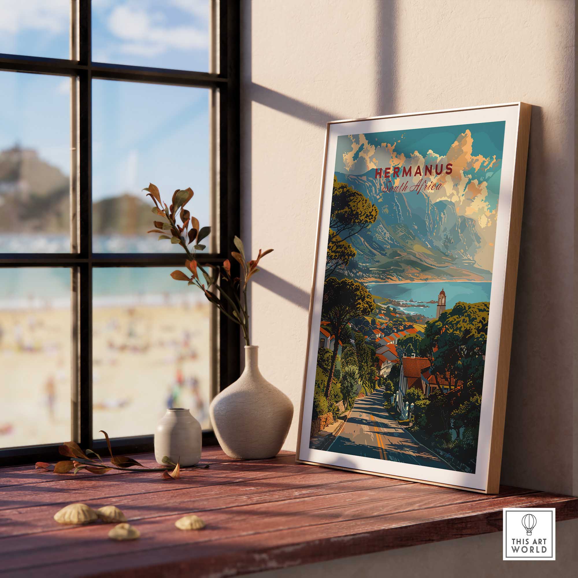 Hermanus Art Print South Africa framed on a wooden table with ocean view, showcasing vibrant seaside landscape.