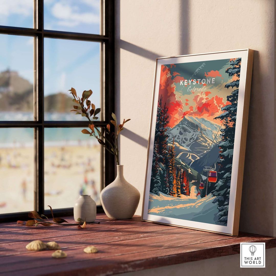 Framed Keystone Colorado art print on a windowsill with mountain and forest scene, bathed in warm sunset light.