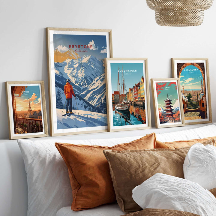 Collection of travel posters featuring Keystone, Copenhagen, and Barcelona against a cozy home backdrop with decorative pillows.