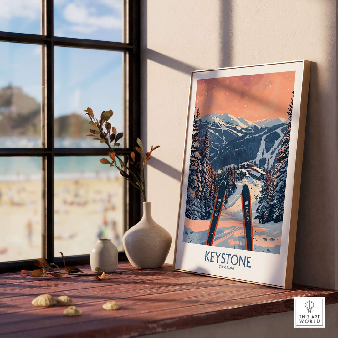 Keystone Wall Art featuring a Colorado ski poster displayed on a wooden windowsill with sunlight, vase, and beach view in background.