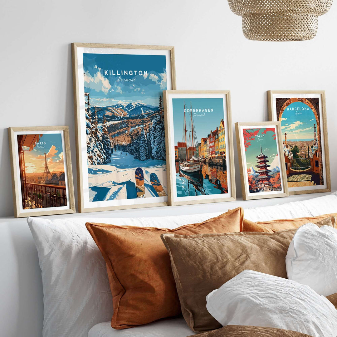 Collection of framed travel posters on a shelf, featuring scenic destinations like Killington, Vermont, Copenhagen, and Barcelona.