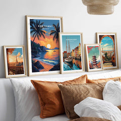Koh Samui Thailand Travel Print and other travel posters displayed on a bed with decorative pillows.