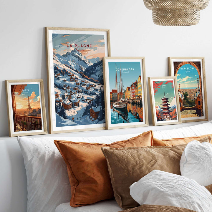 Collection of framed travel posters including La Plagne ski resort, displayed on a sofa with cozy pillows.