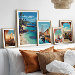 Laguna Beach Print | Southern California Wall Art displayed among other travel prints on a cozy bed with decorative pillows.
