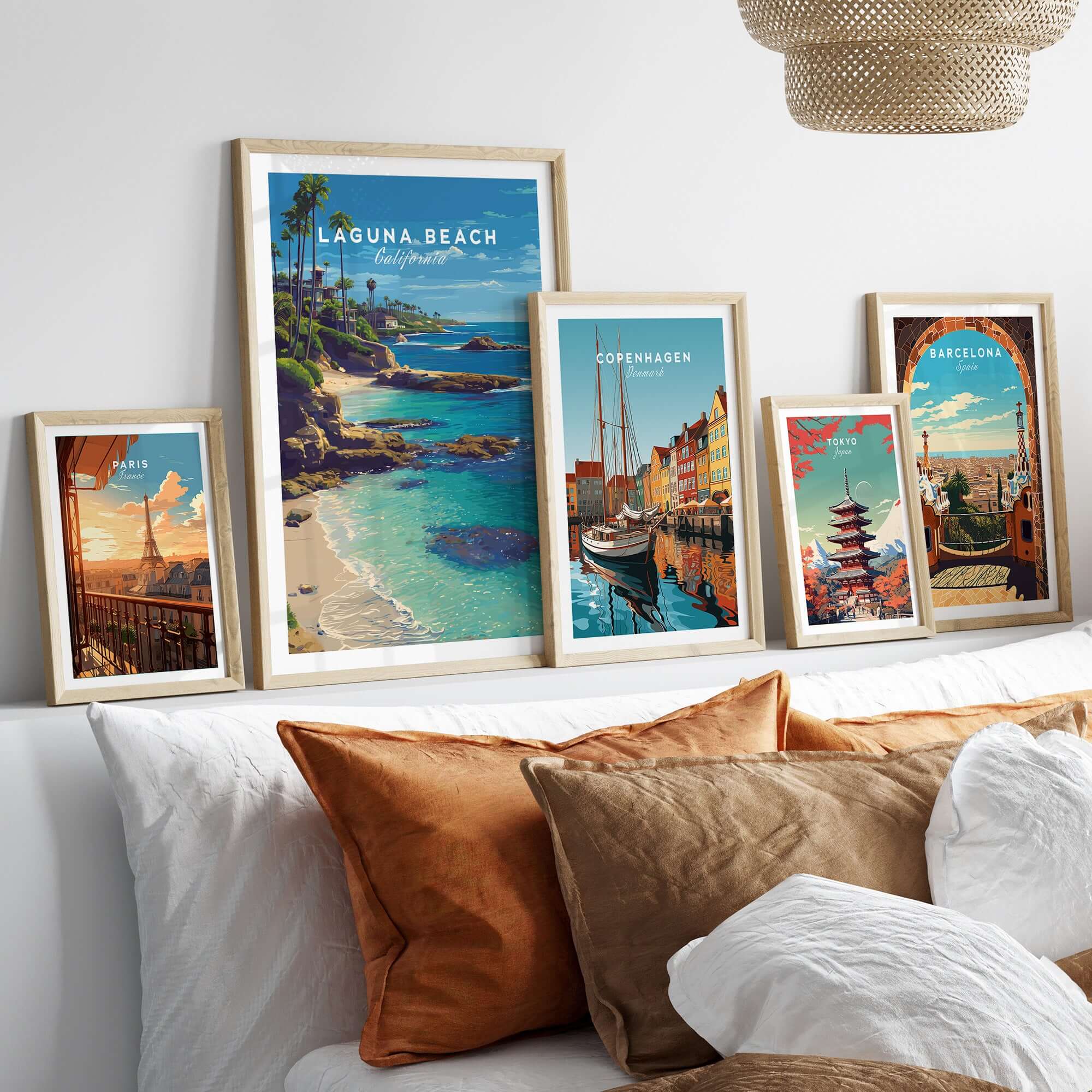 Laguna Beach Print | Southern California Wall Art displayed among other travel prints on a cozy bed with decorative pillows.