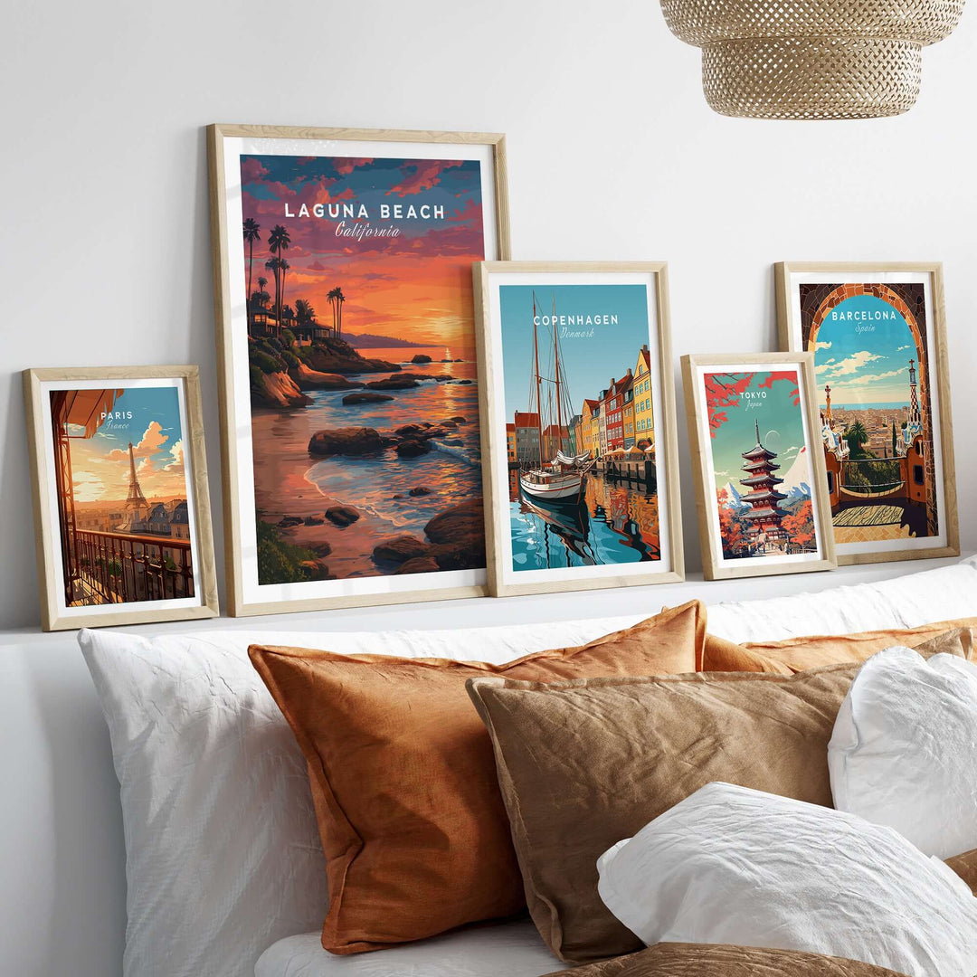 Framed prints of Laguna Beach Pacific Ocean Print and other coastal city artwork displayed above a cozy bed.