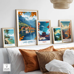 Lake Annecy Travel Poster France displayed among other vibrant travel posters on a stylish couch.