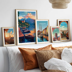Lake Annecy Wall Art displayed among other travel-themed wall art on a cozy bed with pillows.