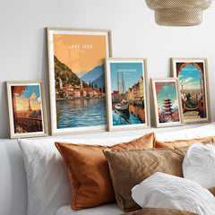 Lake Iseo Print Italy displayed among other travel posters on a stylish couch with decorative pillows.
