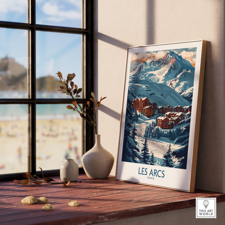 Les Arcs France ski poster displayed on a windowsill, showcasing winter mountain scenery and village buildings in a stylish frame.