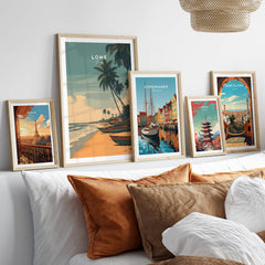 Lomé Togo Travel Poster | Sunset Shoreline Wall Art Print displayed among other travel posters on a stylish couch.