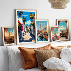 Marbella Travel Print and other travel-themed wall art displayed on a stylish couch with decorative pillows.