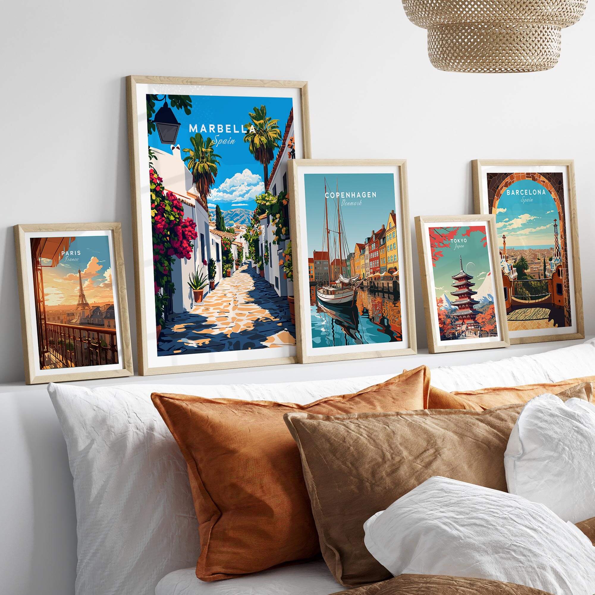 Marbella Travel Print and other travel-themed wall art displayed on a stylish couch with decorative pillows.