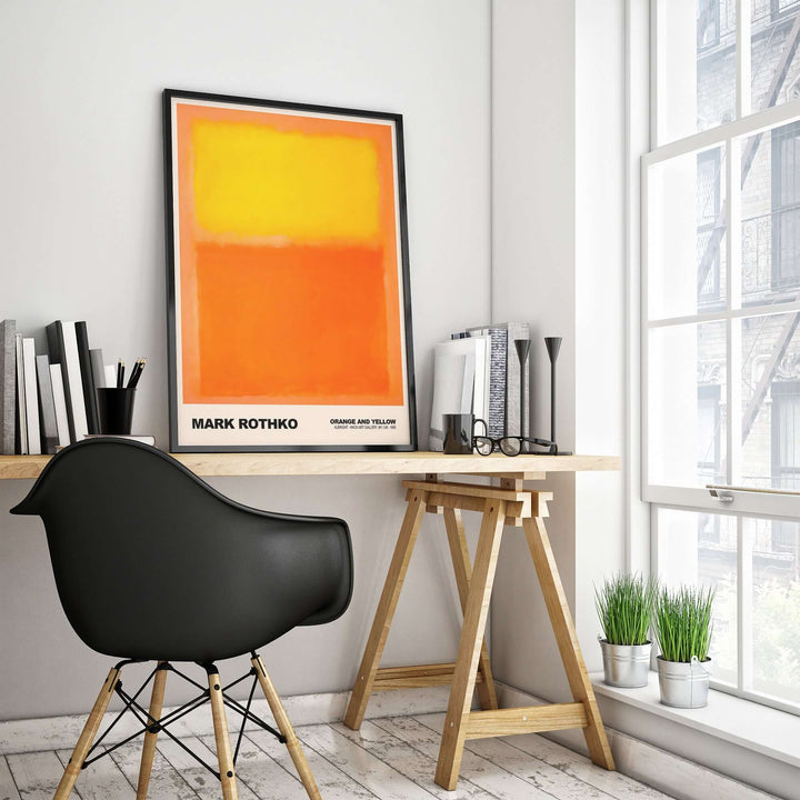 Mark Rothko Orange and Yellow 1956 art print displayed in a modern workspace with a black chair and sunlight.