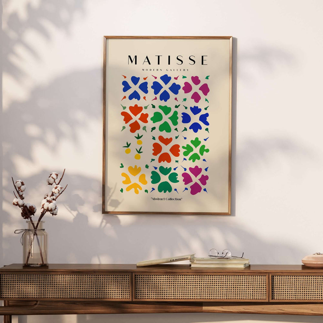 Matisse Abstract Floral Grid Poster with colorful flower shapes on beige background, framed and displayed on a wooden table.