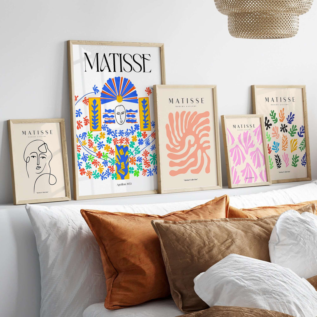 Collection of Matisse art prints in frames on a shelf above colorful pillows in a stylish interior setting.