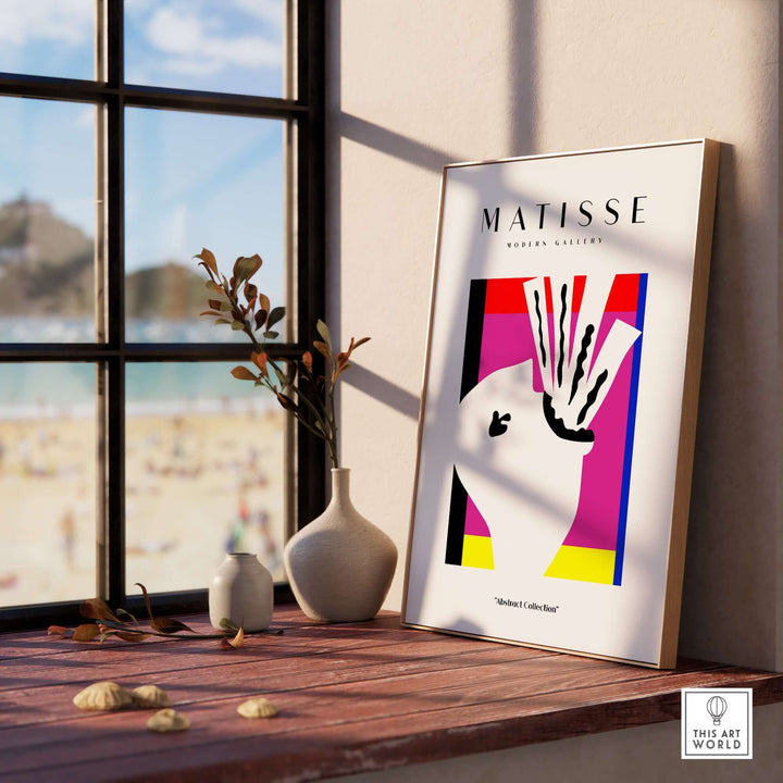 Matisse abstract head art print in modern decor by a window with beach view and decorative vase.