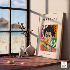 Matisse Art Prints - Abstract Portrait Poster displayed on a shelf with plants, overlooking a beach scene through the window.