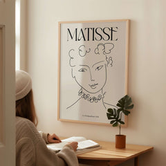 Matisse Art Print La Pompadour 1951 Minimalist Line Drawing Poster displayed on wall with person reading below.