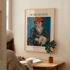 Matisse Art Print - Madras Rouge Red Headdress 1907 Wall Art Poster displayed on a wall with a person reading.
