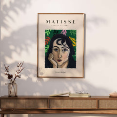 Matisse Art Prints - Pensive Woman Poster displayed on a wall above a wooden table with flowers.