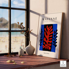 Matisse Art Prints -  Red Coral Black Leaves Blue Frame Poster displayed in a serene room with beach view.