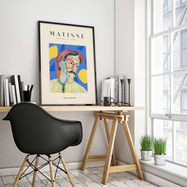 Matisse abstract man portrait poster in a stylish workspace with black chair and greenery.