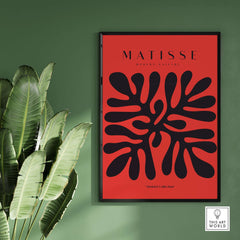 Matisse Art Prints -  Black Abstract Coral Shape Red Poster displayed on a wall with green and plant backdrop.