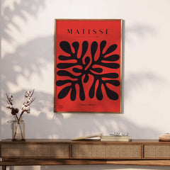 Matisse Art Prints - Black Abstract Coral Shape Red Poster displayed on a wall with a stylish wooden table.
