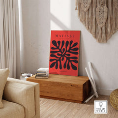 Matisse Art Prints -  Black Abstract Coral Shape Red Poster displayed on a wooden table in a modern living room setting.