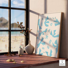 Matisse Art Prints -Blue Abstract Birds Botanical Pattern Poster displayed on wooden ledge with beach view.