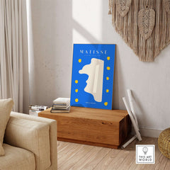 Matisse Art Prints -  Blue Abstract Profile with Yellow Dots Poster displayed on a wooden table in a cozy interior.
