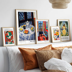 Matisse Art Prints - Still Life Blue Tablecloth Poster displayed on a wall above a cozy sofa with decorative pillows.