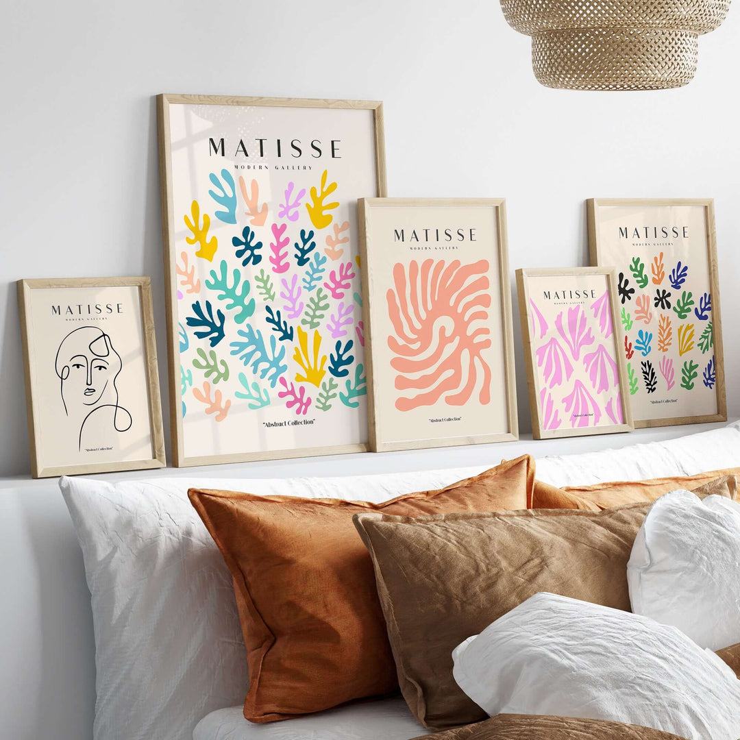 Colorful Matisse art prints displayed on a shelf above a cozy bed with orange and white cushions.