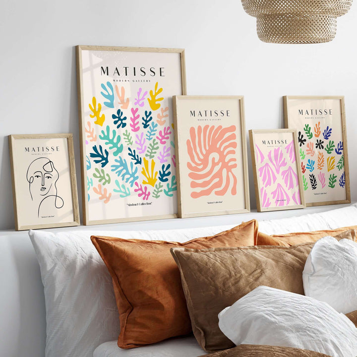 Colorful Matisse art prints displayed on a shelf above a cozy bed with orange and white cushions.