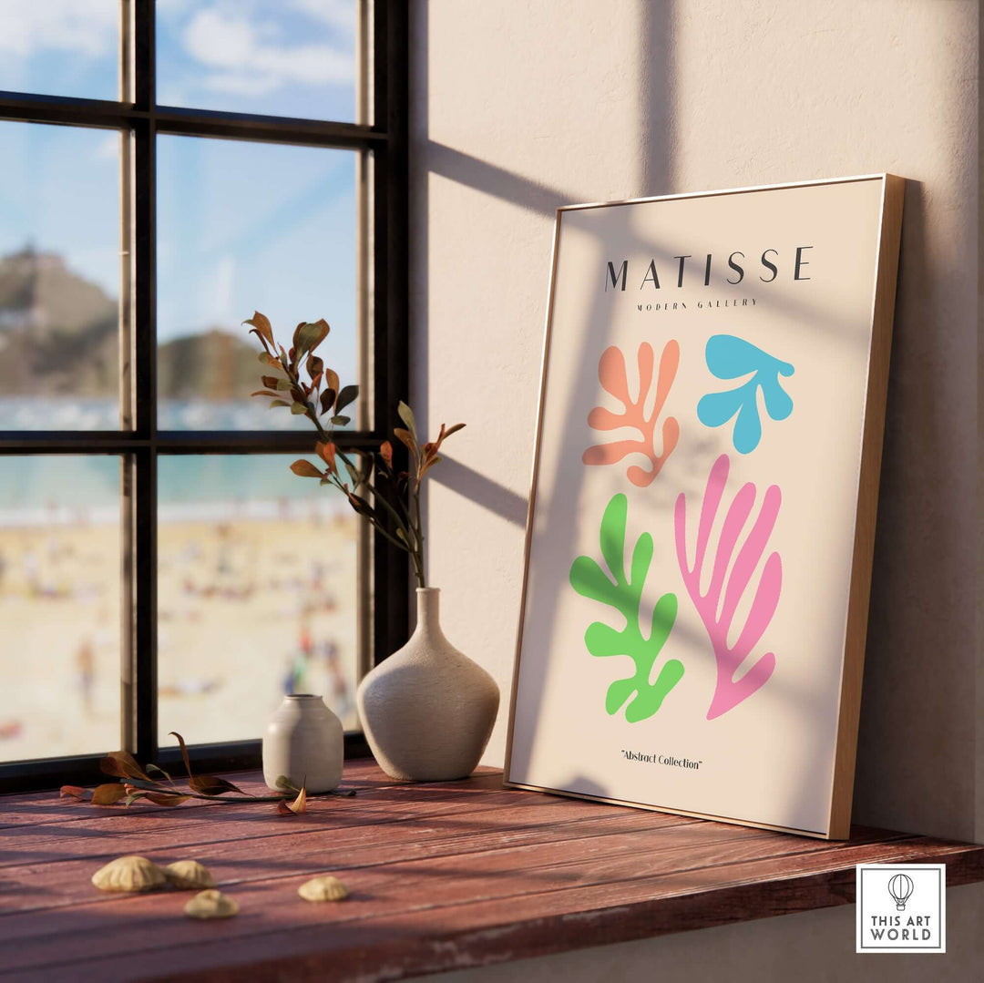 Matisse art print featuring colorful abstract shapes in pink, blue, and green, displayed by a window with a beach view.
