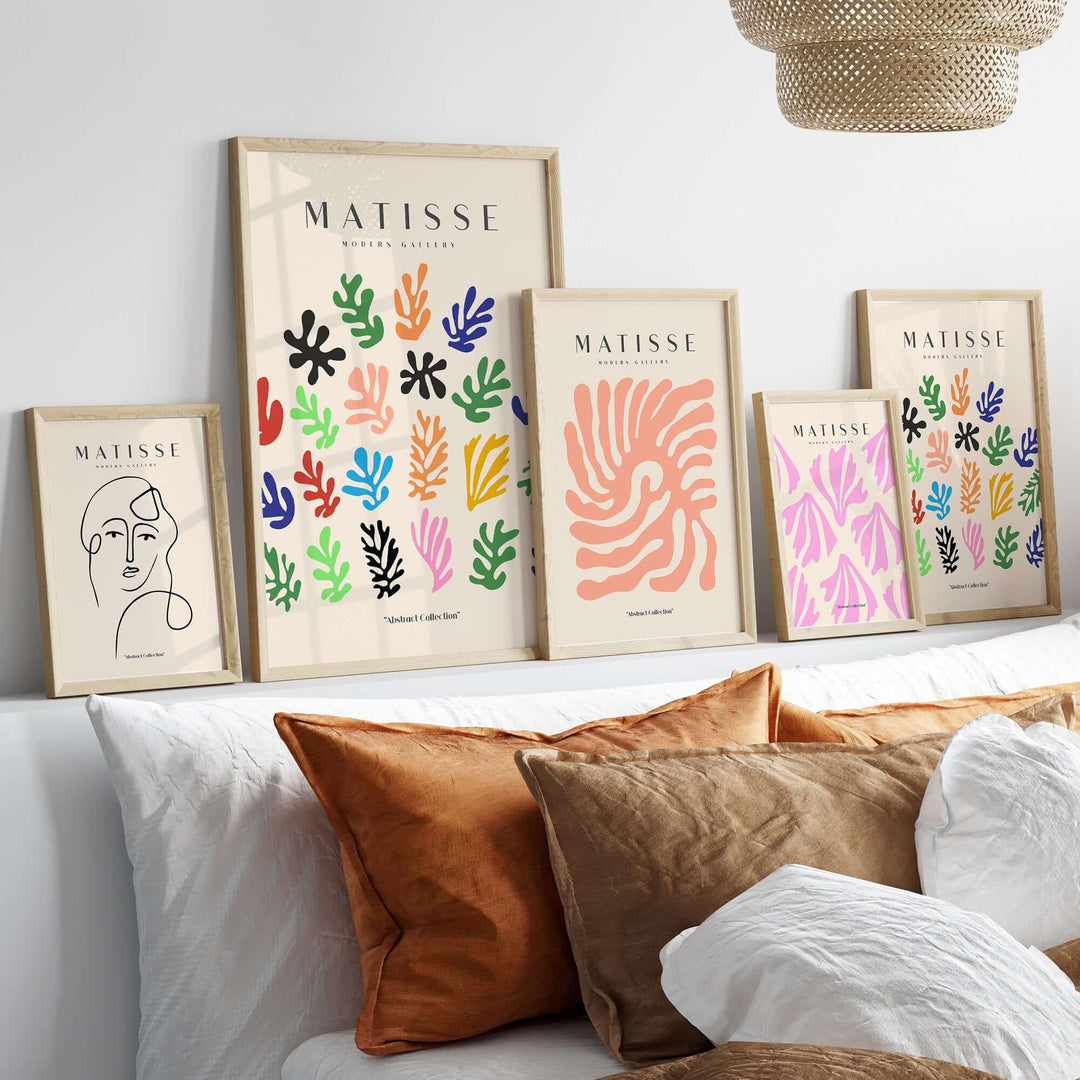 Matisse art prints featuring colorful abstract botanical shapes displayed on a shelf above a sofa with decorative pillows.
